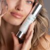 Butelka NMF xpress cream przy policzku modelki, obok bryła lodu