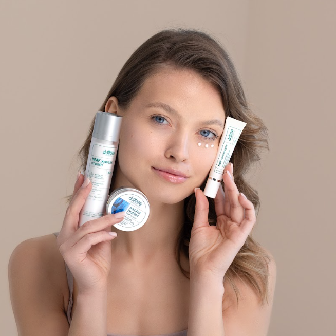 Modelka trzymająca zestaw kosmetyków: krem pod oczy, krem nawilżający NMF oraz masło do twarzy