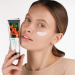 Profil kobiety z nałożonym białym preparatem na policzku trzymającej tubkę peelingu Puratore