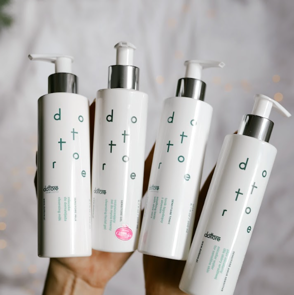 Cztery butelki delikatnych kosmetyków do oczyszczania twarzy: mleczko, żel, tonik i płyn micelarny.